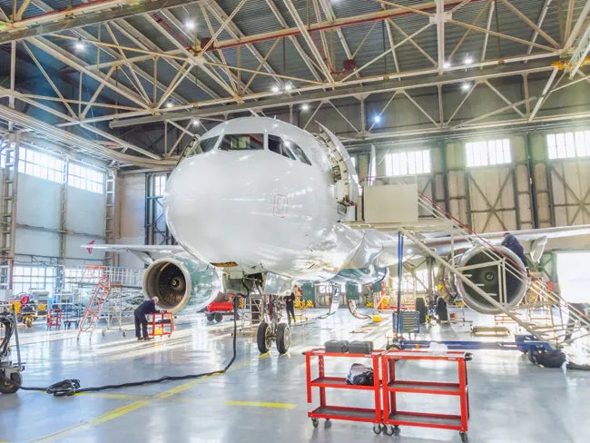 Airplane inside a large hangar with maintenance activities