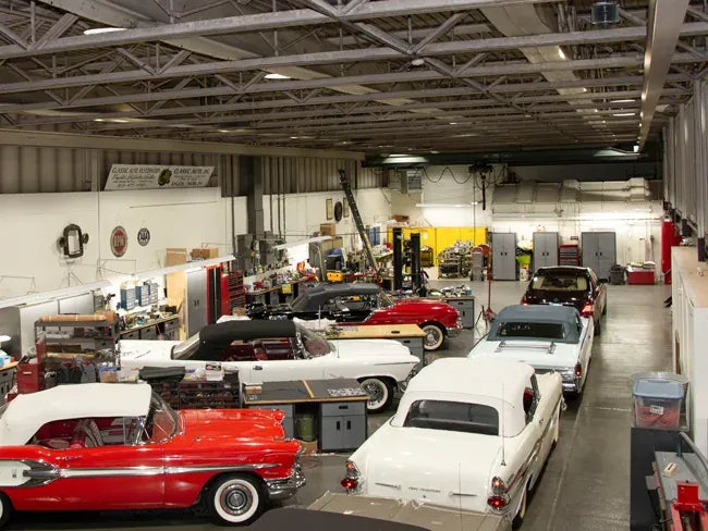 Interior of a warehouse with vintage cars and equipment.