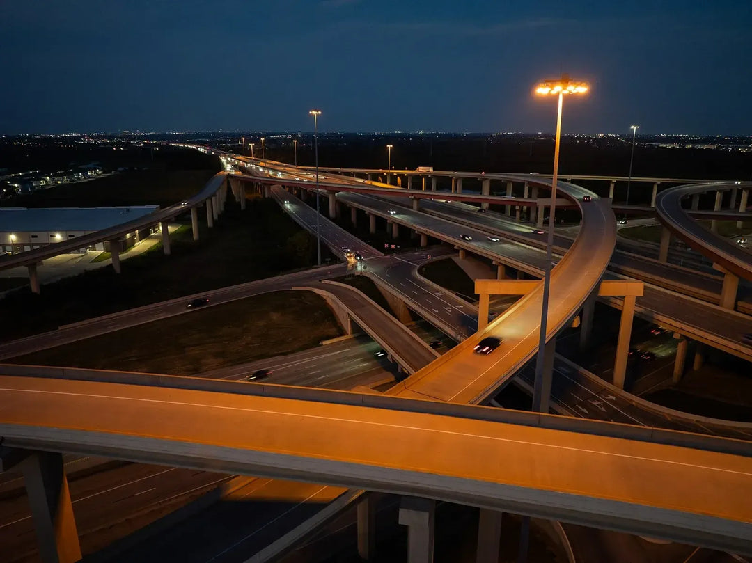 Highway interchange at night with illuminated roadways and structures.