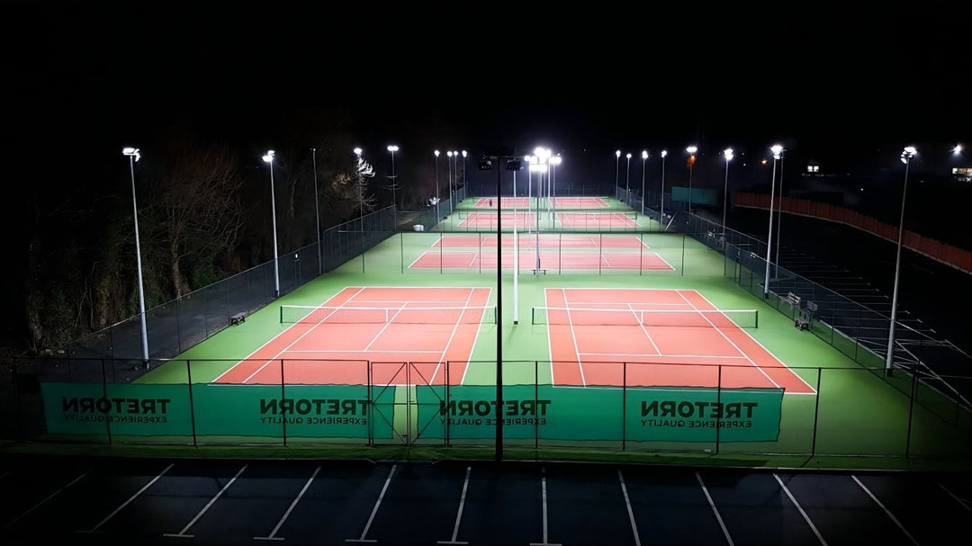 Tennis courts at night with floodlights on a dark sky background