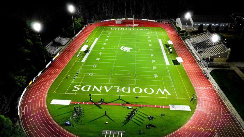 Football field with 'Christian Woodlands' branding at night